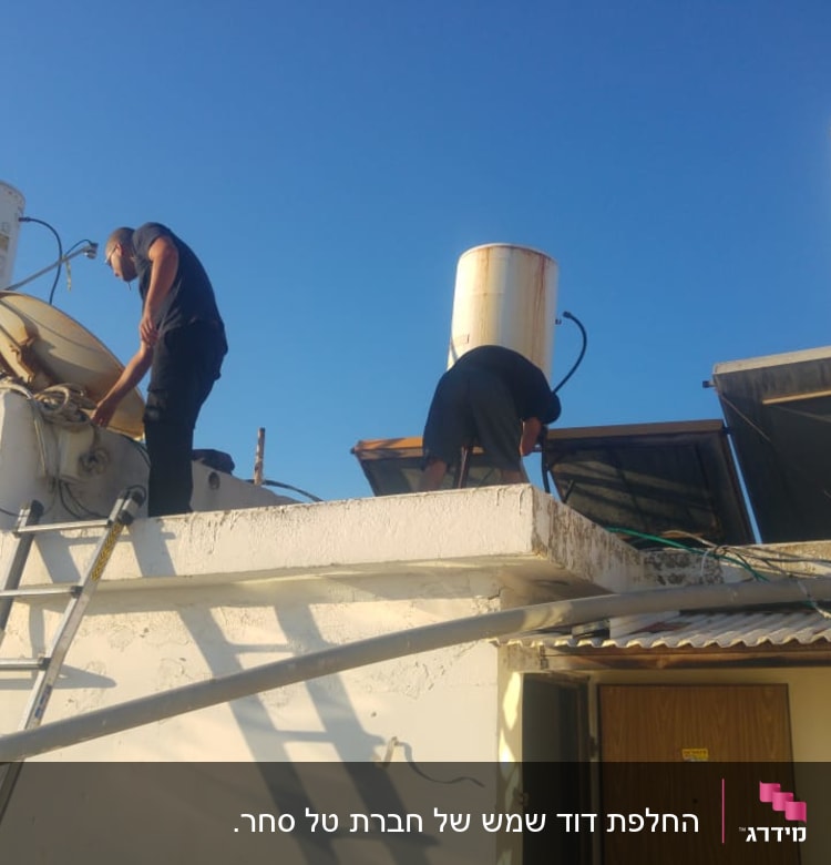 אנשים מתקנים דוד שמש על גג עם קולטים